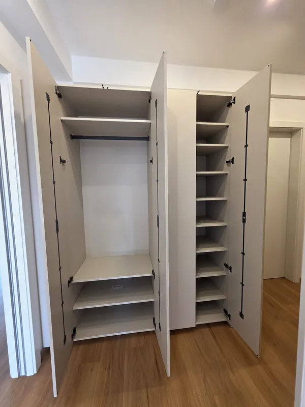 Geöffneter Einbauschrank mit Kleiderstange, Fachböden und schmalem Regal