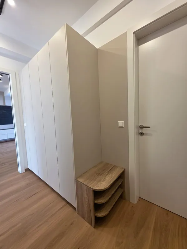 Grifflose Schrankwand im Flur mit offenem Holzregal als Sitzbank
