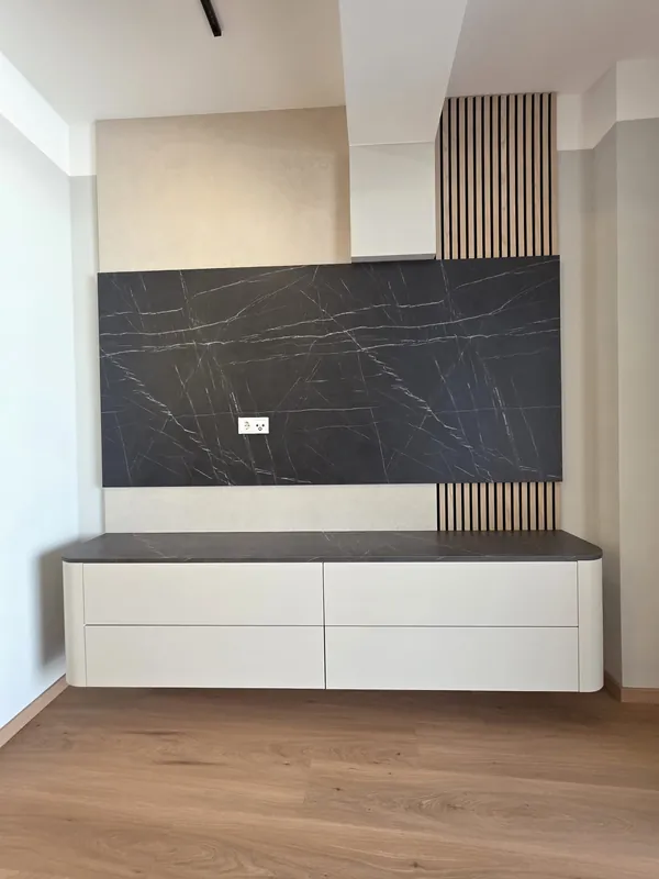 Schwebendes weißes Sideboard vor dunklem Wandpaneel in Marmoroptik und Holzlamellen